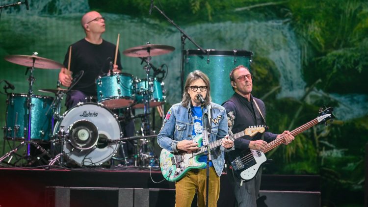 Weezer Will Still Play Coachella After Scott Shriner’s Wife Was Shot By Police